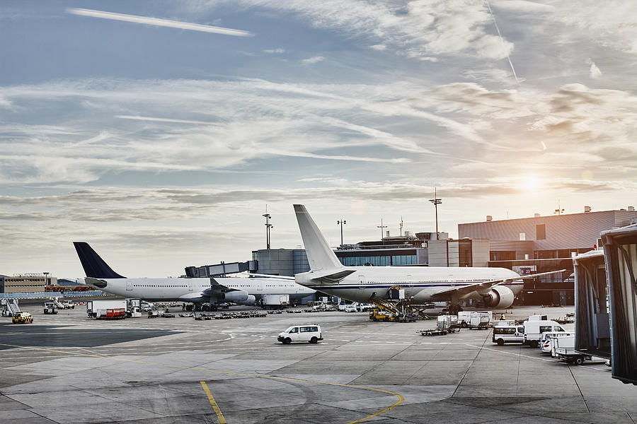 Airplanes and vehicles on the apron at sunset Photograph by Westend61