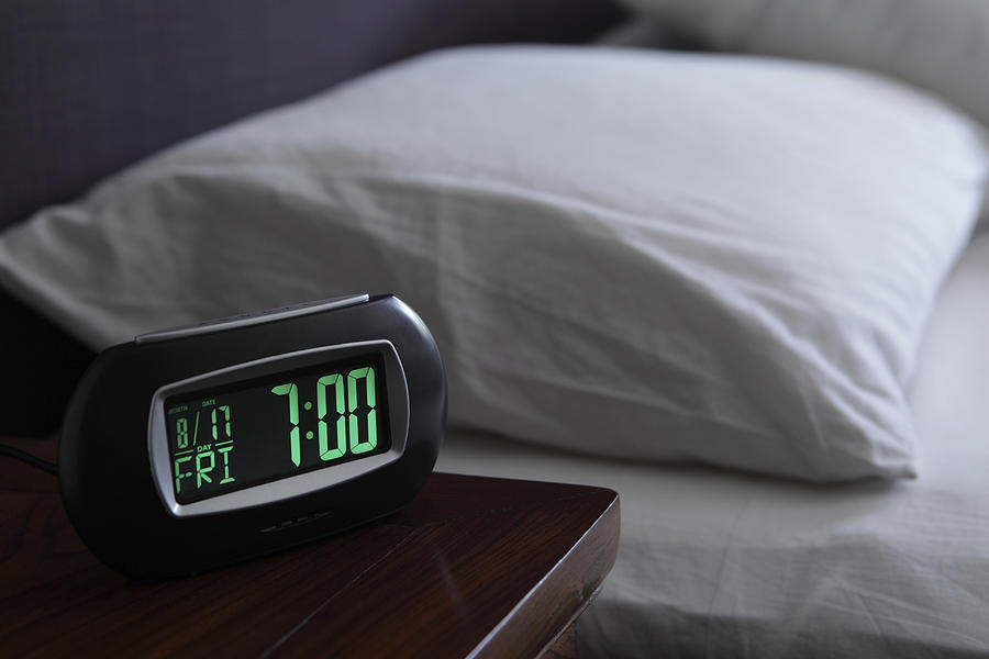 Alarm clock by bed Photograph by Image Source