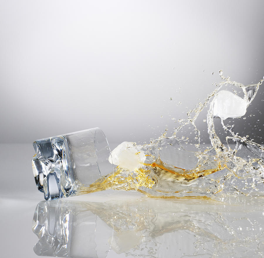 Alcohol and ice cubes spilling from falling highball glass Photograph by Robert Daly