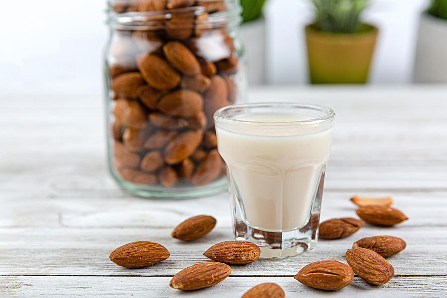 Almonds in a jar, a glass of almond milk Photograph by Phamai Techaphan