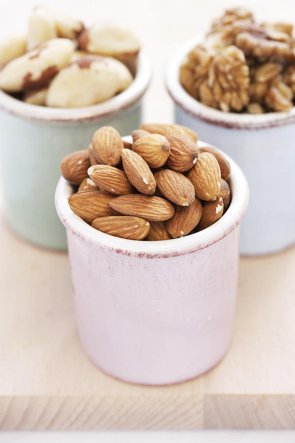 Almonds, walnuts and brazilian nuts in containers, close-up Photograph by Martin Poole