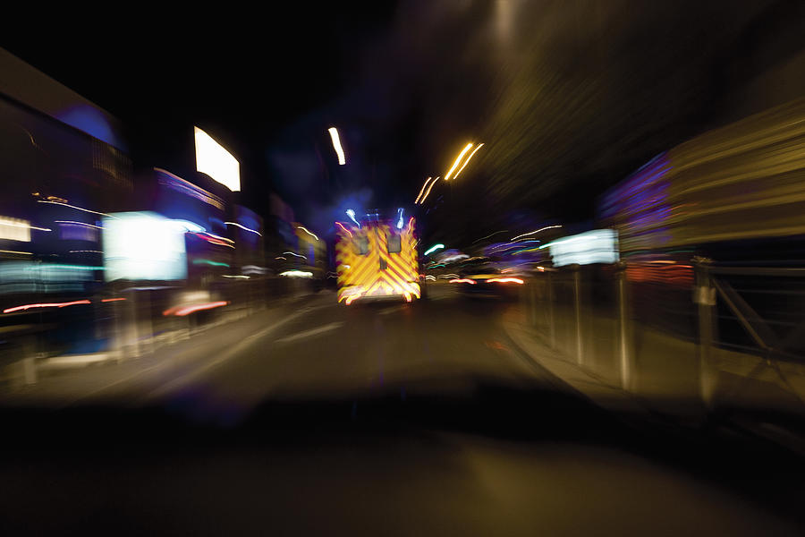 Ambulance rushing down street at night Photograph by PhotoAlto/James Hardy