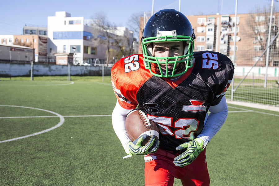 American football player holding the ball during a match Photograph by Westend61