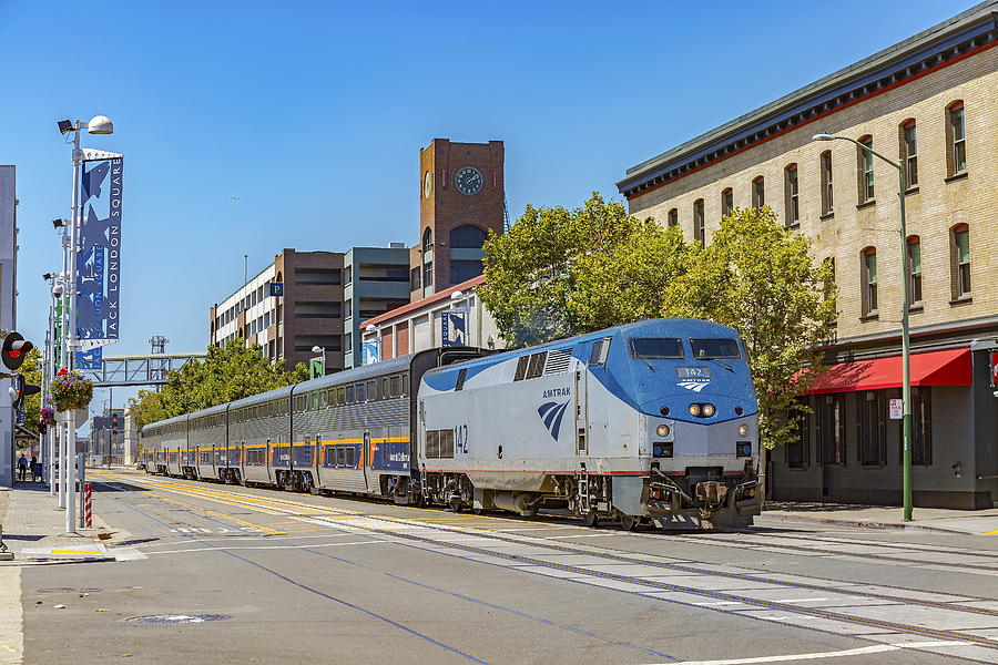Amtrak train on street, Jack London Square, Oakland, California Photograph by John Kirk