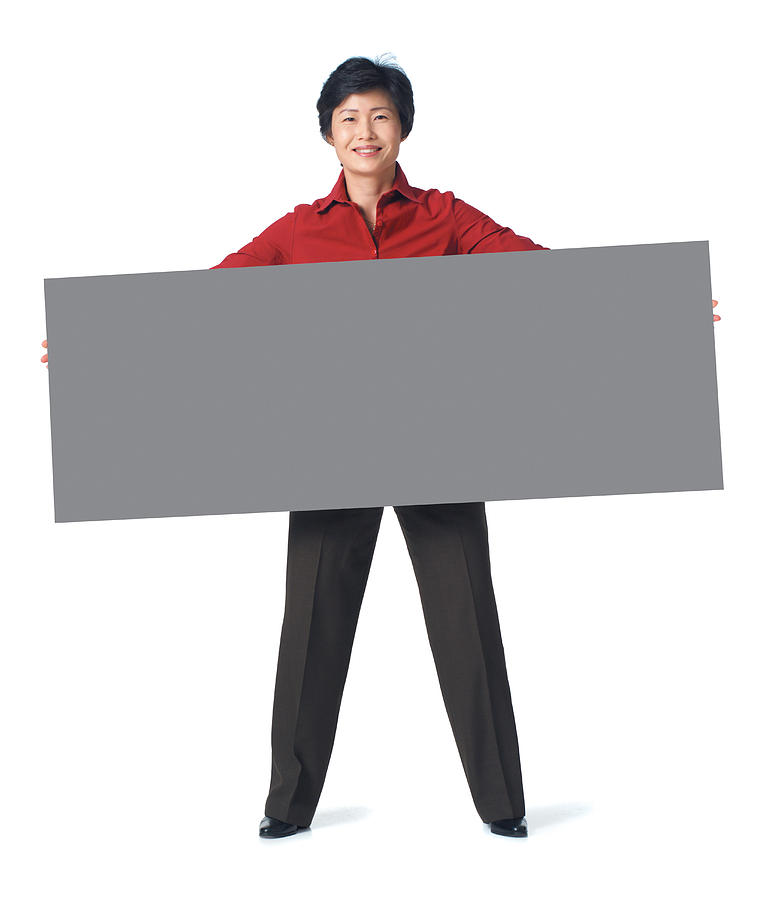 An Adult Asian Woman In A Dark Grey Pants With A Red Blouse Holds A Large Sign In Front Of Herself Photograph by Photodisc