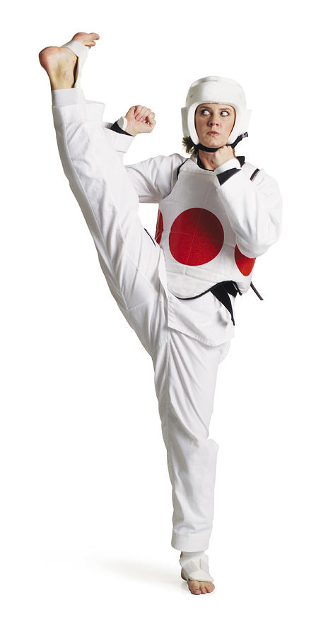 An Adult Caucasian Female Martial Arts Expert Wearing Padding And Protective Headgear Kicks High Up Into The Air To Her Right Photograph by Photodisc