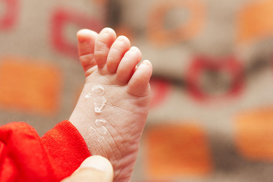An adult hand holding a baby feet. Photograph by Nazman Mizan