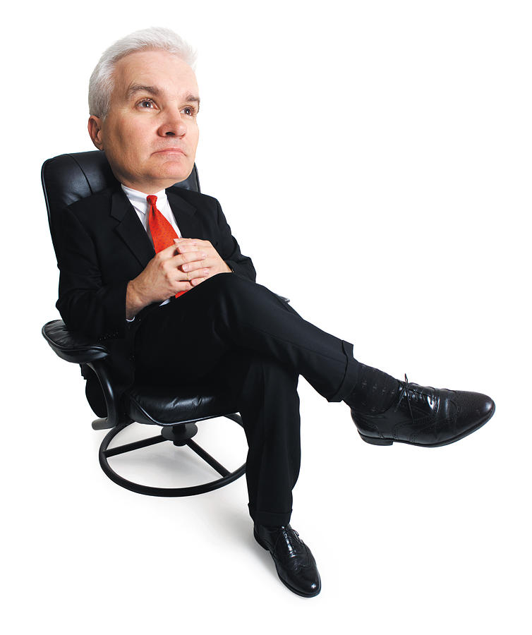 An Adult Male Caucasian Business Executive In A Dark Suit Sits Back In His Chair As He Thinks Photograph by Photodisc