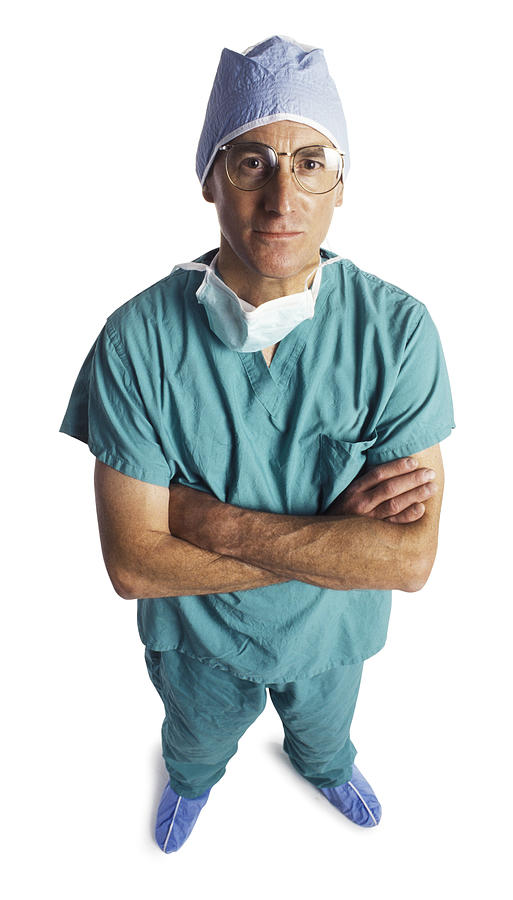 An Adult Male Doctor In Scrubs And A Surgical Mask Folds His Arms And Looks Up At The Camera Photograph by Photodisc