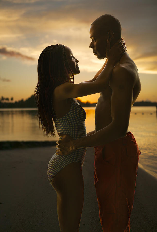 An African American Couple In Swimsuits Embrace Lovingly On A Beach At Sunset Photograph by Photodisc