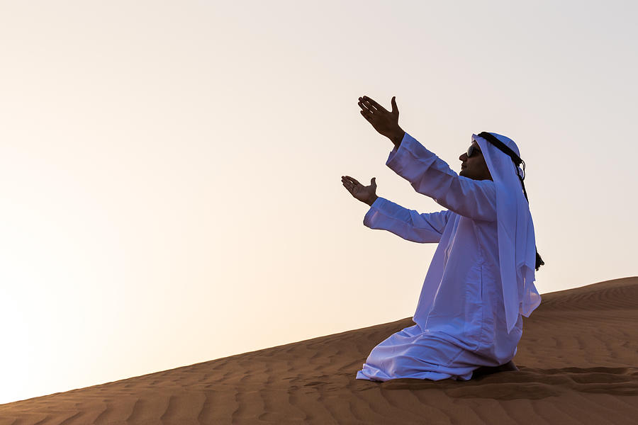 An Arab man praying in desert, Dubai Photograph by GCShutter