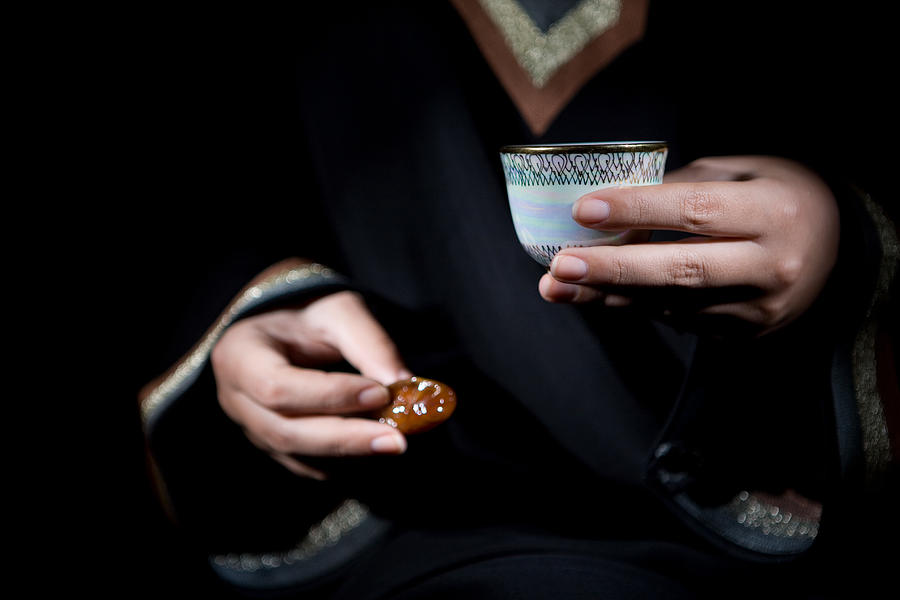 An arab woman holding a bowl of dates and gawa (Arabian Coffee). Photograph by Charney Magri