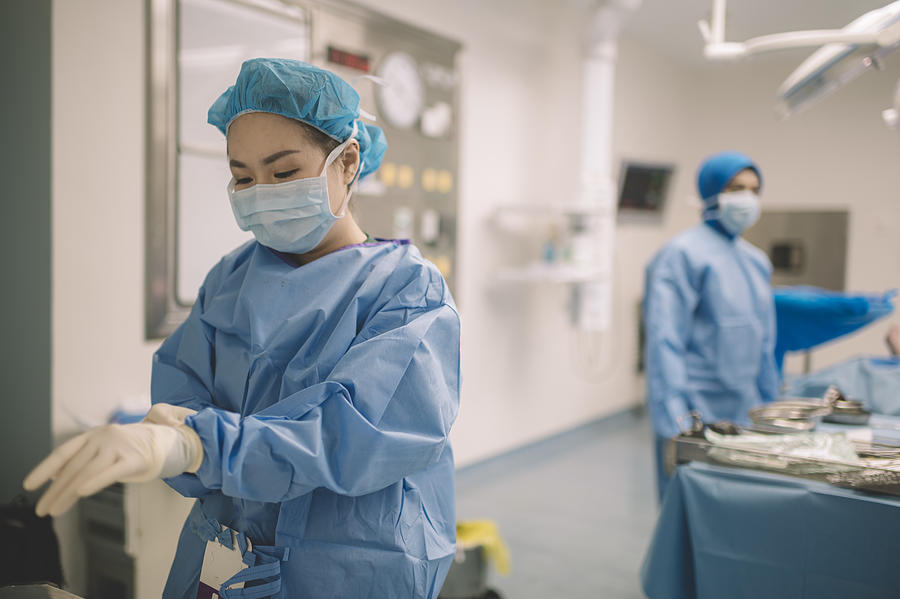 An Asian Chinese Female Surgeon Doctor Is Wearing Surgical Gloves Before The Surgery In Operating Room Photograph by Chee Gin Tan