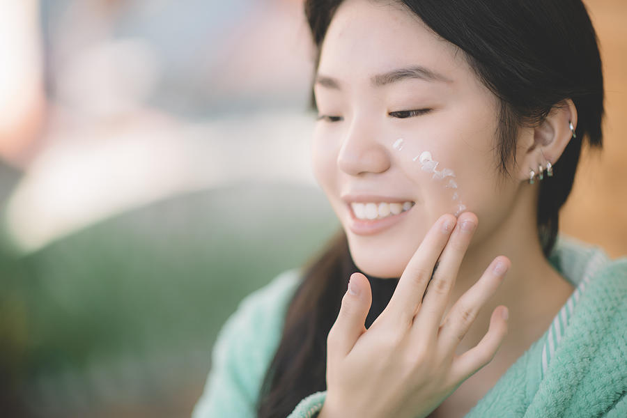 An Asian Chinese Teenager Girl Applying Moisturiser Facial Cream On Hand And Face Photograph by Chee Gin Tan