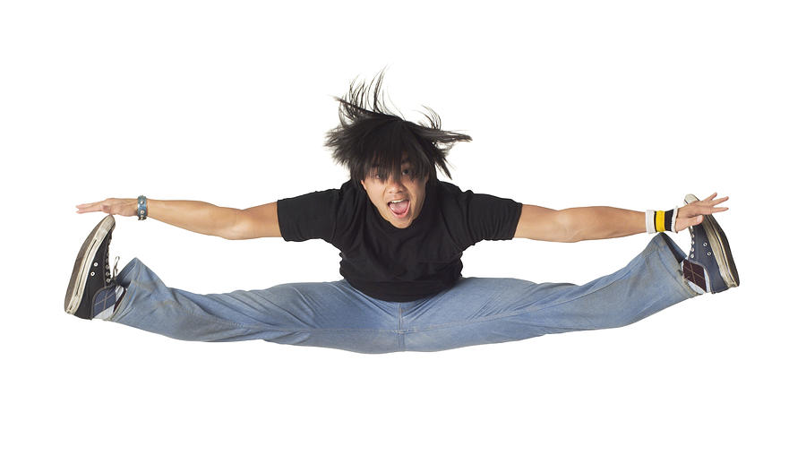 An Asian Male Teen In Jeans And A Black Shirt Jumps Up And Does The Splits In The Air Photograph by Photodisc