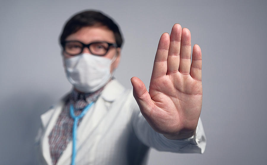 An Asian Or Chinese Doctor In A Medical Mask And Glasses Shows A Warning Stop Sign With His Hand. Photograph by Aleksandr Zubkov
