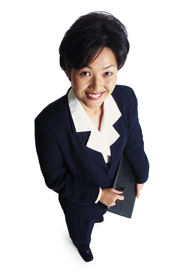 An Attractive Asian Business Woman Holds A Notebook And Smiles As She Looks Up At The Camera Photograph by Photodisc