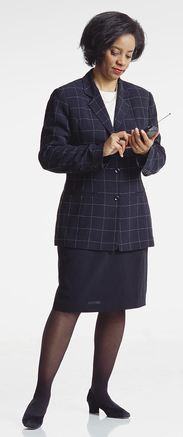 An Attractive Middle Aged African American Businesswoman With Short Hair Dressed In A Dark Business Suit Dialing A Cell Phone Photograph by Photodisc