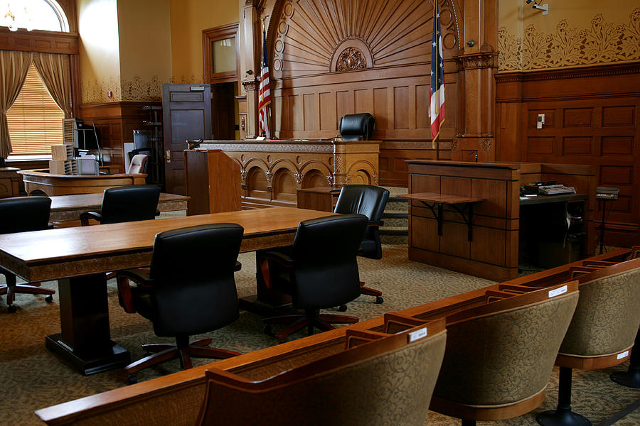 An empty, brown-paneled courtroom with flags Photograph by Ftwitty