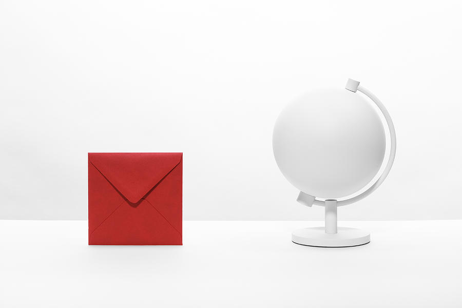 An envelope on a desktop next to a desk globe Photograph by Creative Crop