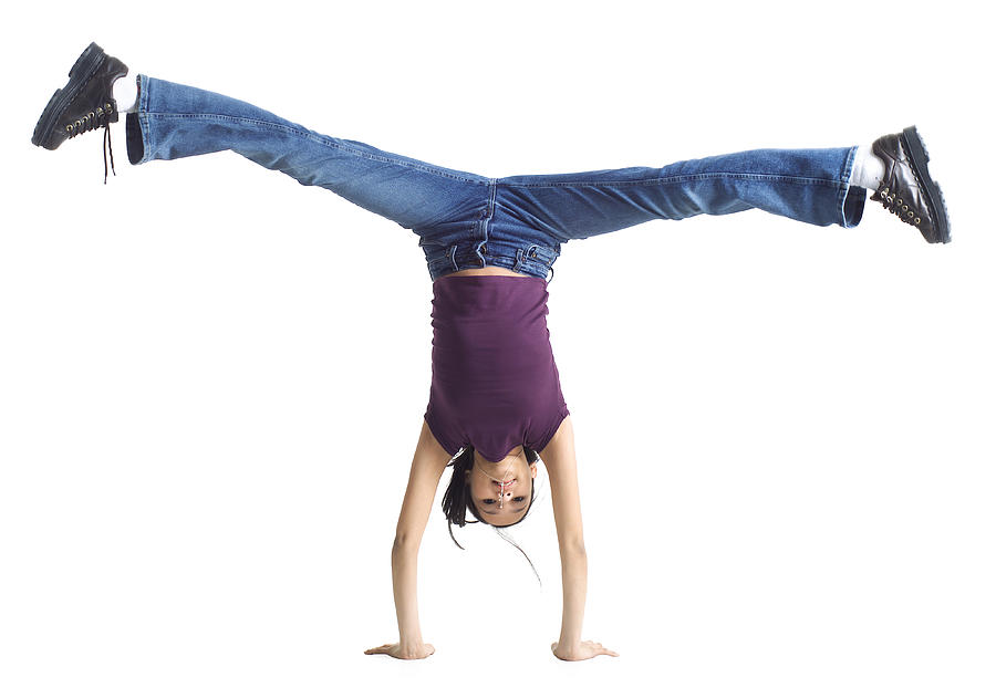 An Ethnic Teenage Girl In Jeans And A Purple Shirt Does A Cartwheel Photograph by Photodisc