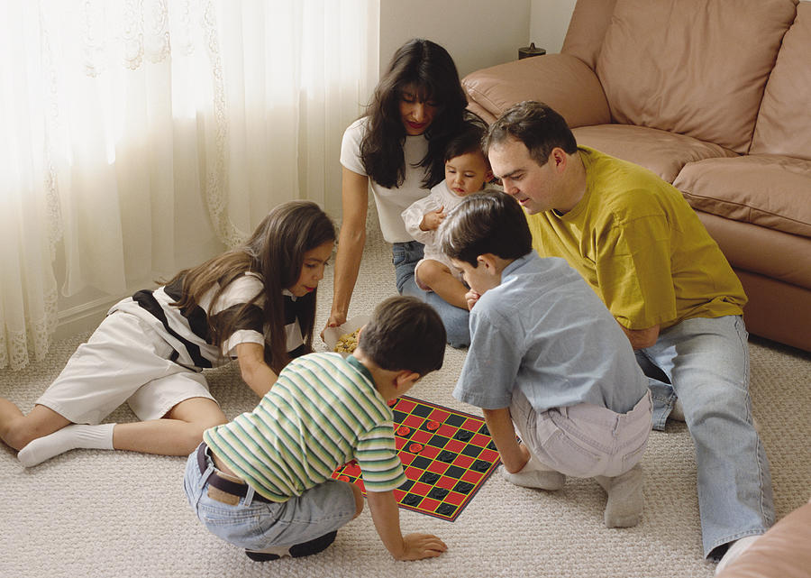 An Ethnically Mixed Family Sits In A Circle Playing A Game Photograph by Photodisc