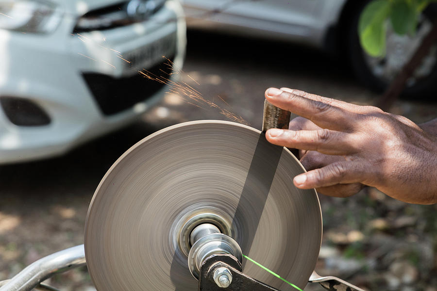 Man Sharpening His Pocket Knife with a Whetstone on a Rustic