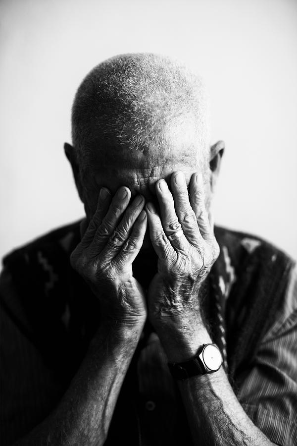 An old man covering his face with his hands in grief  Photograph by Delihayat