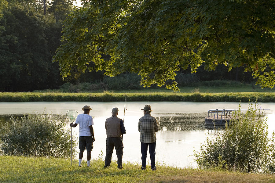 Anglers by lake Photograph by Image Source