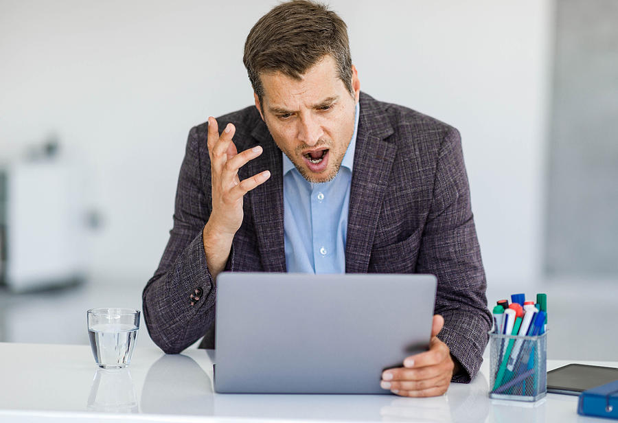 Angry businessman arguing during video call over computer in the office. Photograph by Skynesher