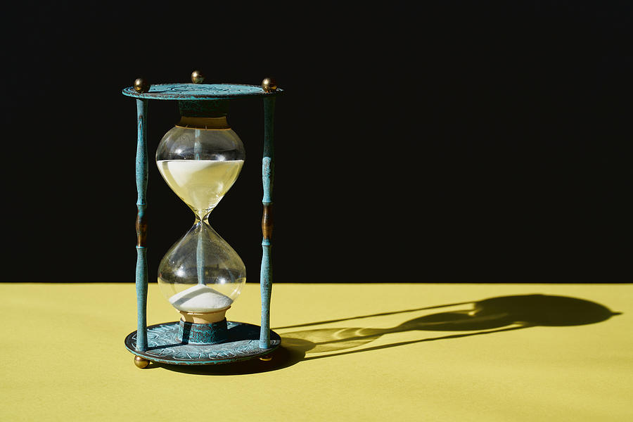 Antique Blue Hourglass time with sand running through against black and yellow background Photograph by Ruben Bonilla Gonzalo