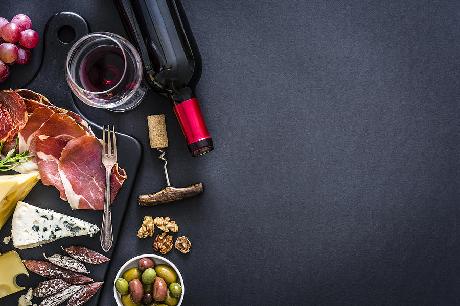 Appetizer frame: red wine, Iberico ham and cheese on rustic table Photograph by Fcafotodigital