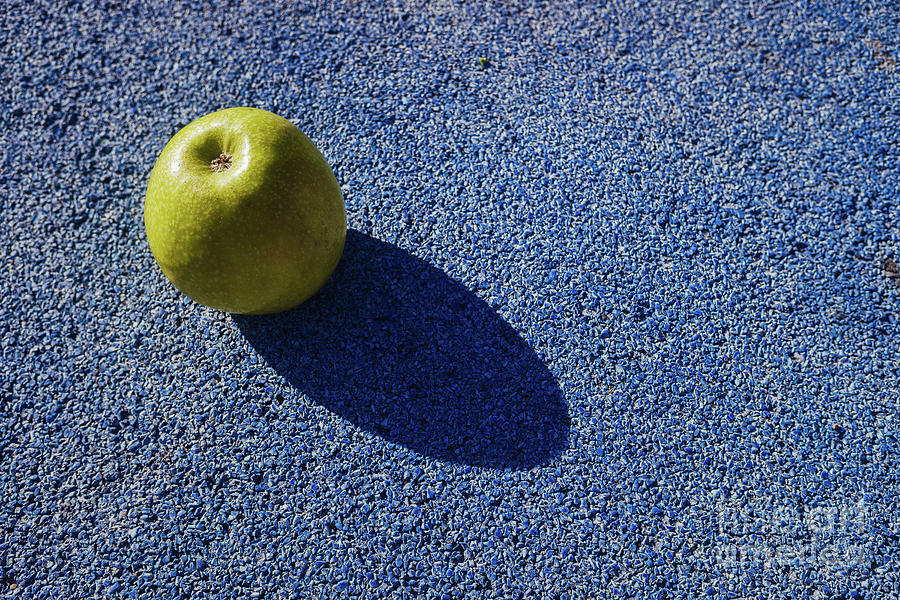 Apple isolated on the rough ground of strange color. Photograph by Joaquin Corbalan
