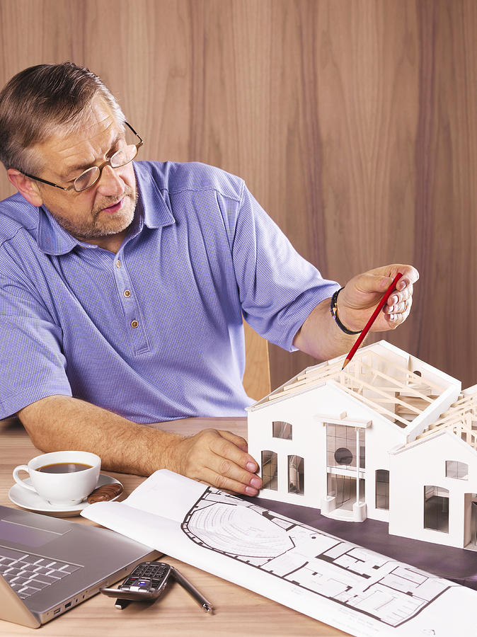 Architect with model house on desk Photograph by Peter Dazeley