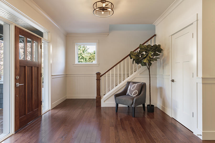 Armchair and tree in house entryway Photograph by Mint Images