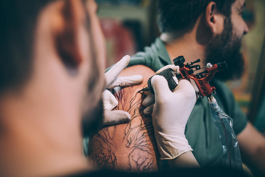Artist tattooing a man in studio Photograph by South_agency