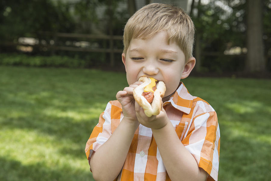 Asian boy eating hot dog Photograph by Jose Luis Pelaez Inc