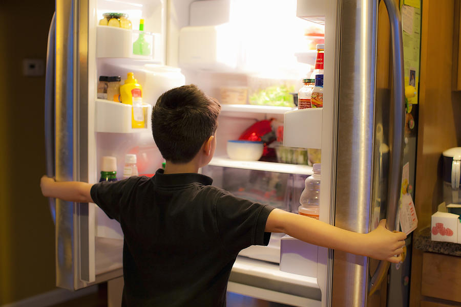 Asian boy searching through refrigerator Photograph by Jed Share/Kaoru Share