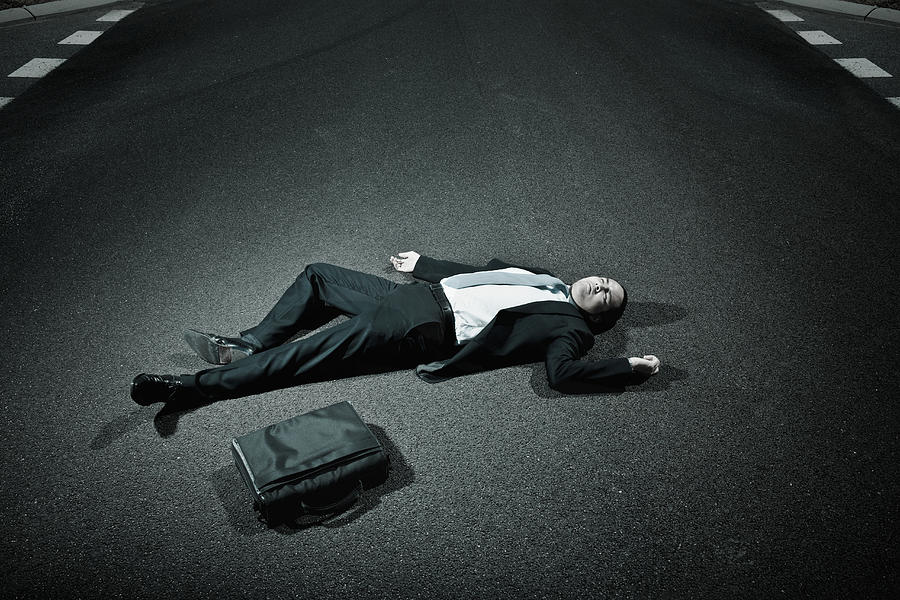 Asian businessman laying on asphalt roadway Photograph by Jacobs Stock Photography Ltd