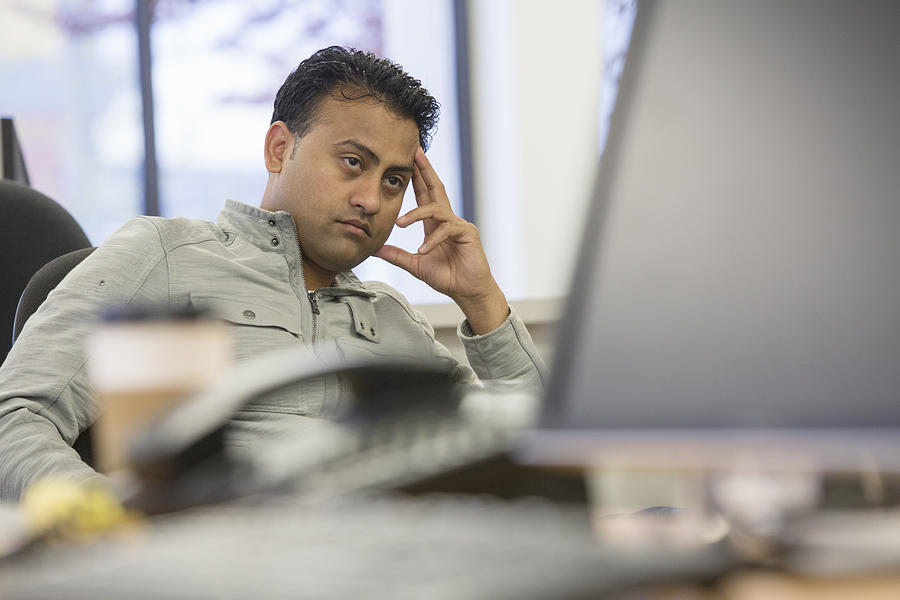 Asian businessman thinking at desk in office Photograph by Jetta Productions Inc
