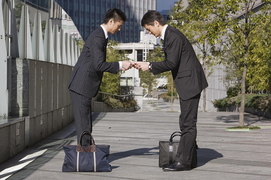 Asian businessmen bowing Photograph by Jeremy Woodhouse