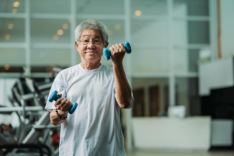 Asian chinese active senior male exercising and workout with dumbbell in gym room during weekend activity Photograph by Marcus Chung 