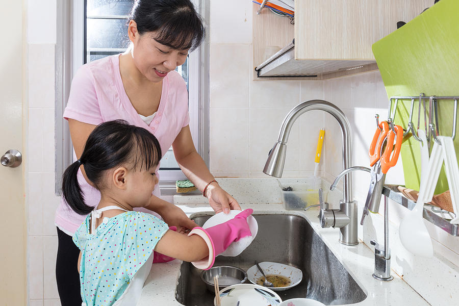 Asian Chinese little girl helping mother washing dishes Photograph by Kiankhoon