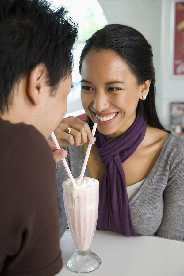 Asian couple sharing milkshake Photograph by Hill Street Studios