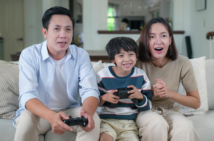 Asian family play video game with joystick togather in living ro ...