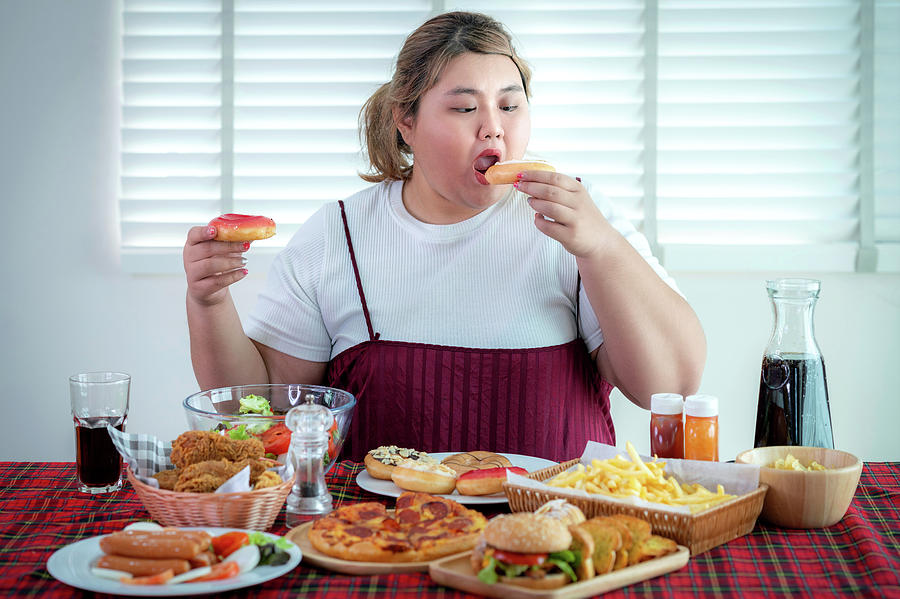 Asian fat girl hungry and eat a junk food on the table Photograph by Anek Suwannaphoom