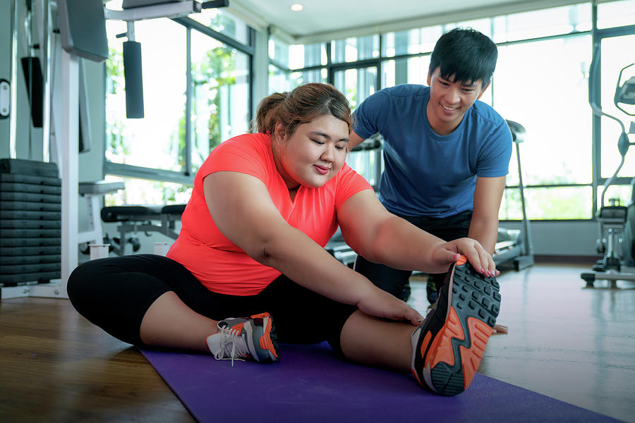 Asian fat girl relax after exercise with ber trainner in fitness Photograph by Anek Suwannaphoom