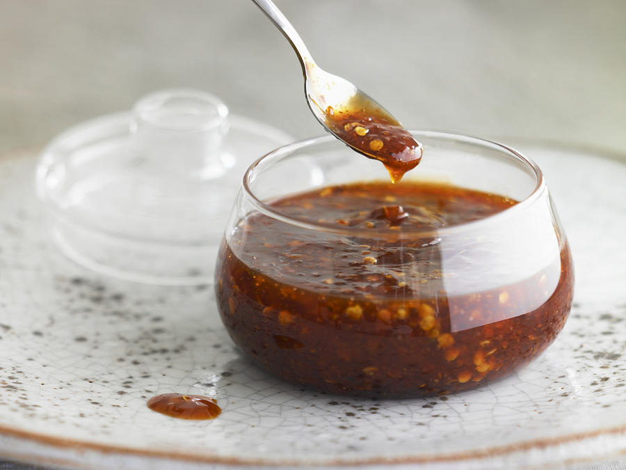 Asian hot sauce in glass bowl with lid and spoon Photograph by Maren Caruso