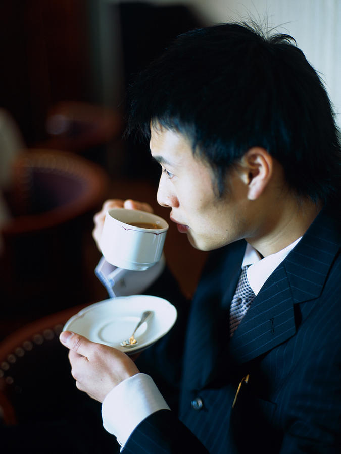 Asian Man sipping tea at a caf? Photograph by Dex Image