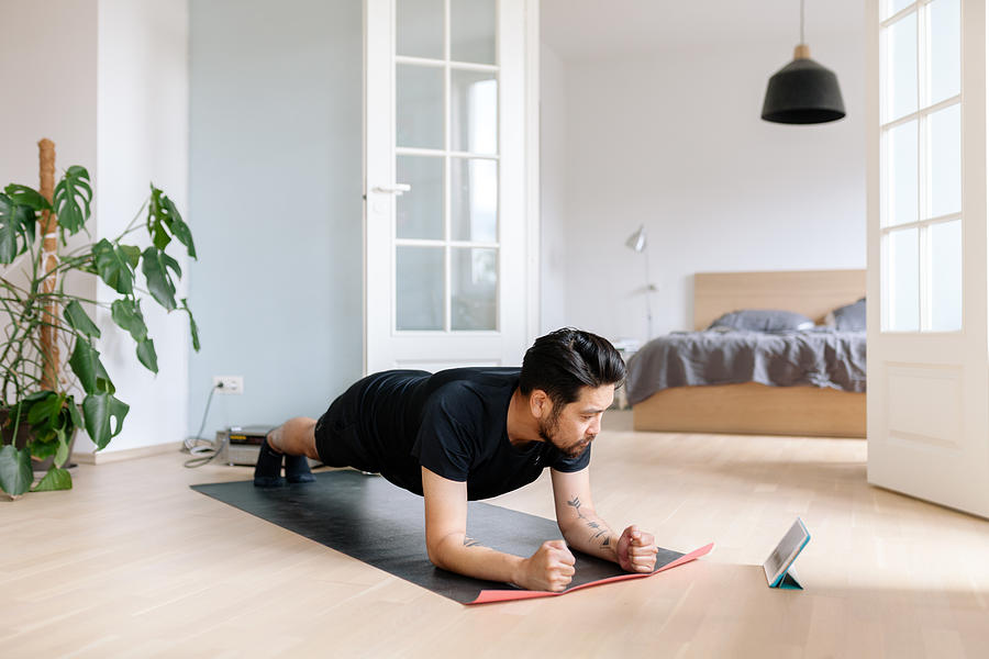 Asian man uses digital tablet to lean plank position Photograph by Visualspace